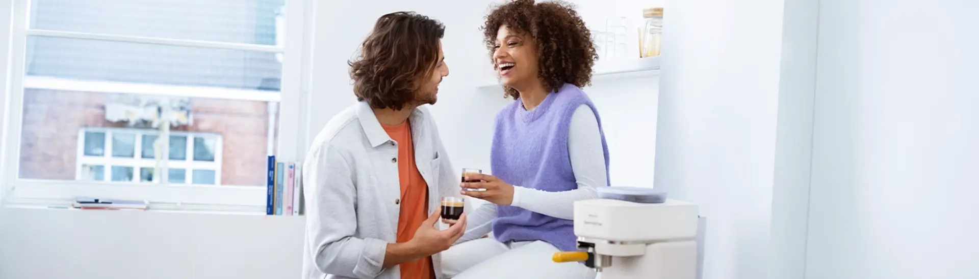 Koppel lachend koffie drinkend bij de Philips Baristina espressomachine Koppel lachend koffie drinkend bij de Philips Baristina espressomachine
