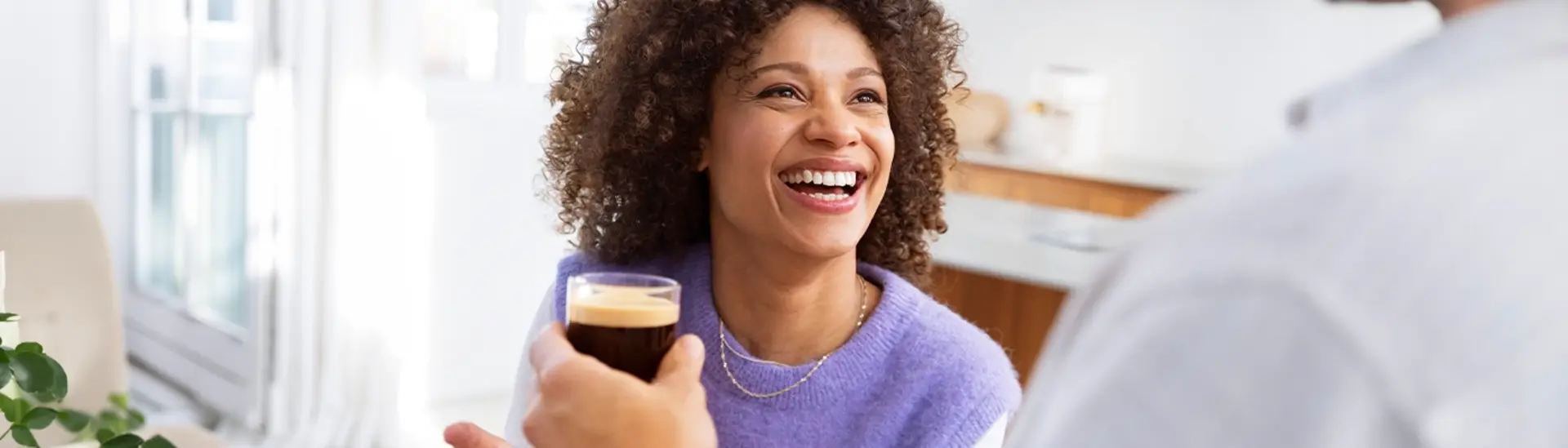 Uśmiechnięta kobieta sięgająca po szklankę kawy Uśmiechnięta kobieta sięgająca po szklankę kawy