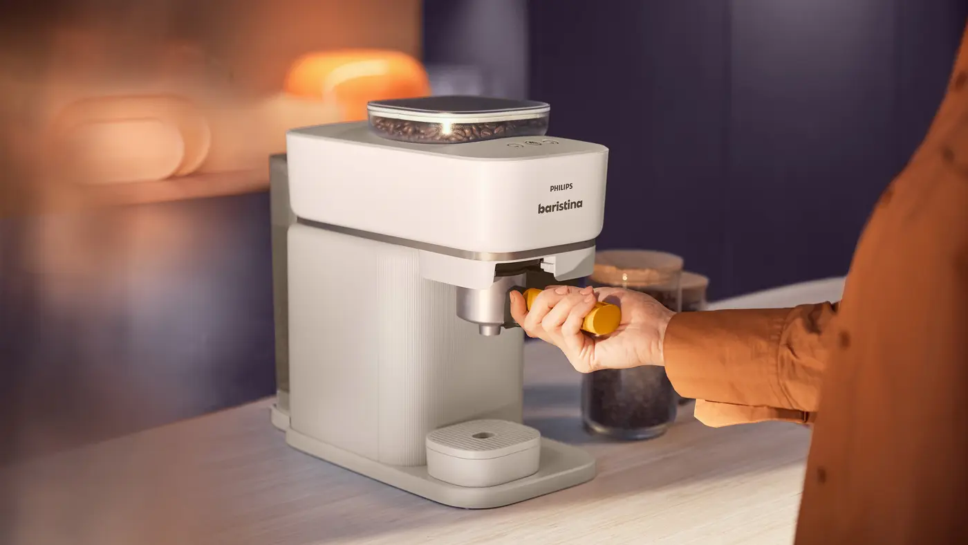 Personne préparant du café avec la machine à expresso Philips Baristina dans une cuisine chaleureuse. Personne préparant du café avec la machine à expresso Philips Baristina dans une cuisine chaleureuse.